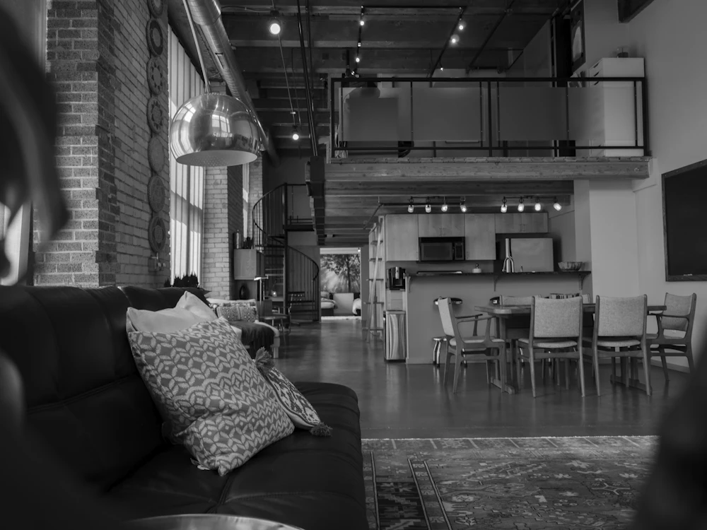 Industrieloft mit Ledersofa, Essbereich und einer Galerie unter der Decke.